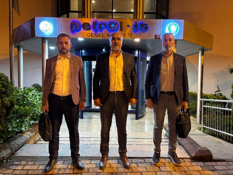 Petrol-İş Genel Merkezi önünde, üç kişi resmi kıyafetlerle duruyor. Arkada 'petrol-iş GENEL MERKEZİ' yazılı tabela görünmekte.