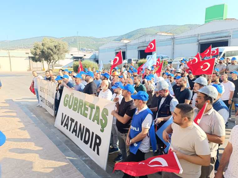 Gübretaş emekçilerinin toplu sözleşme görüşmeleri üzerine düzenledikleri protesto. İşçiler, GÜBRETAŞ yazılı pankartlar tutarak sloganlar atıyor. Arka planda Türk bayrakları ve dağ manzarası görünüyor.
