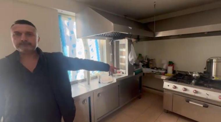 A man pointing towards a commercial kitchen, showcasing its appliances and cleanliness.